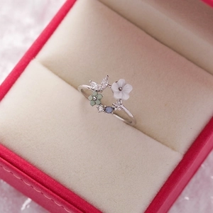 Detailed view of floral ring with resin petals and blue crystals on velvet