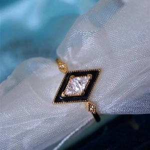Detailed macro view of a gold geometric ring with black enamel and a zircon on mesh fabric
