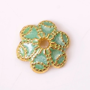 Gros plan d'une perle fleur en émail vert clair avec bords dorés pour bijoux DIY