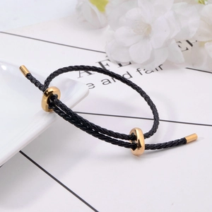 Bracelet tressé noir réglable avec accessoires dorés 3D sur fond de fleurs blanches