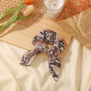 Detail of snake print scrunchie with bow tie design on a stylish flat lay background