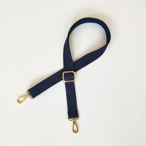 Détail de la bandoulière réglable en tissu bleu foncé avec crochets en métal doré