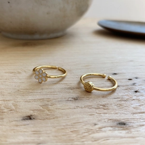 Detail of 925 sterling silver mini rings with daisy and star patterns on wood