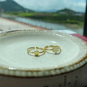 Detail of 925 silver gold rings with starburst and flower patterns on a white plate