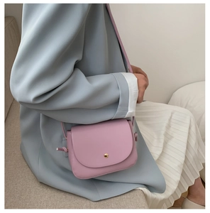 Chic lavender saddle bag styled with a soft blue blazer and a pleated cream skirt