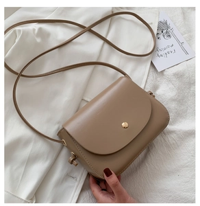 Detail of khaki semi-circle crossbody bag with golden metal buckle and faux leather texture