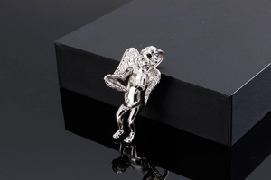 Detailed view of a silver angel cupid pendant made of polished stainless steel on a black box