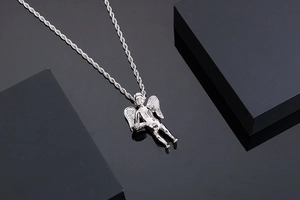 Detailed view of a silver cherub angel pendant with a twist chain on a dark base
