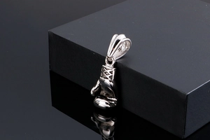 Macro shot of silver polished boxing glove pendant showing detailed metallic texture