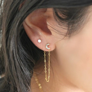 Detail of asymmetric moon earring with zircons, pearls and thin gold chain link