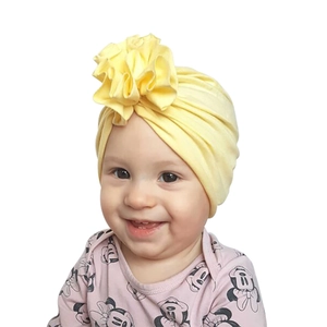 Détail du bonnet turban jaune pour bébé avec une grande fleur en tissu 3D sur le devant