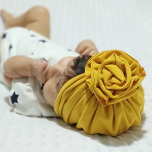 Détail d'un bonnet turban pour bébé en coton jaune avec une grande fleur faite à la main