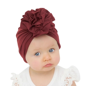 Détail de la grande fleur plissée sur un bonnet turban en coton bordeaux pour bébé