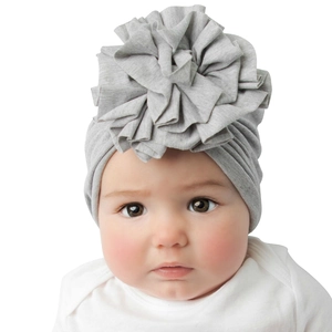 Détail du bonnet turban gris pour bébé avec une grande fleur en tissu plissé doux