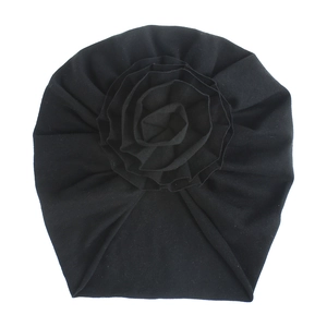 Détail du bonnet noir en coton pour bébé orné d'une grande fleur en tissu multicouche
