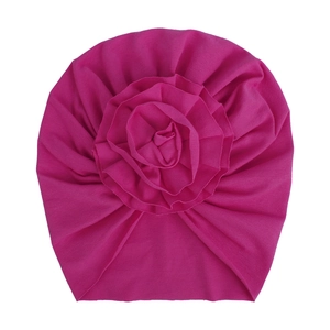 Détail d'un bonnet turban pour bébé avec rose en tissu et coton plissé fuchsia