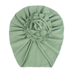 Détail du bonnet turban en coton tricoté vert haricot avec une grande fleur en tissu fait main