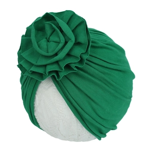 Détail du bonnet turban bébé vert foncé avec une grande fleur en tissu plissé