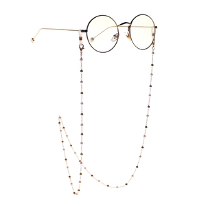 Round golden metal frame glasses with elegant pearl beaded chain on white background