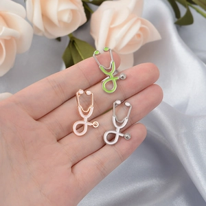 Detailed view of three stethoscope enamel brooches in green, rose gold, and silver finishes