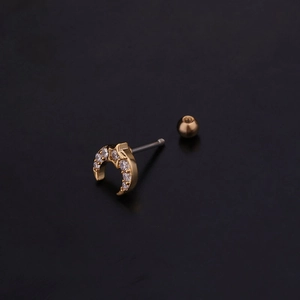 Detailed macro view of golden crescent moon cartilage stud with zircon and screw ball back