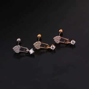 Close-up of heart-shaped zircon cartilage earrings in silver, gold, and rose gold finish