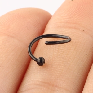 Macro view of a black stainless steel nose ring with metal ball on a fingertip