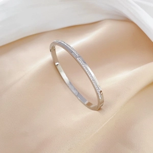 Silver stainless steel oval bangle with full crystal pavé on luxury silk background