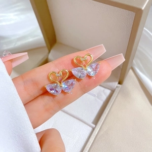 Elegant gold swan stud earrings with light purple crystals shown on fingers