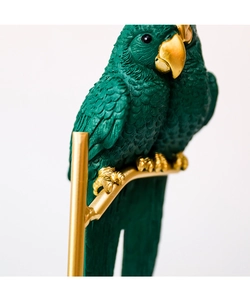 Detailed macro view of green resin parrots with realistic feathers and gold accents