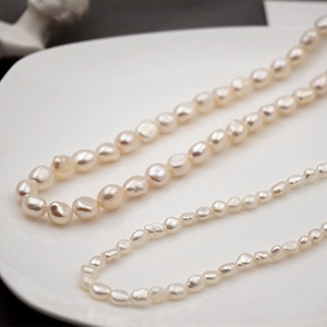 Eleganti collane di perle d'acqua dolce bianche su un piatto di ceramica minimal
