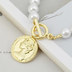 Macro shot of baroque pearl bracelet featuring gold OT clasp and queen coin pendant