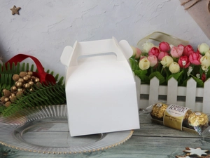 Close-up of white paper gift box on a decorative gold plate with festive ornaments