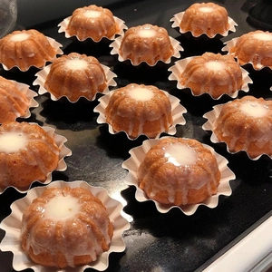 Dettaglio di mini bundt cake dorate con glassa bianca in pirottini di carta a fiore