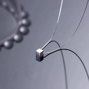 Minimalist S925 sterling silver cube necklace on reflective dark background