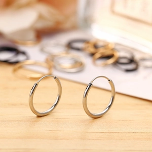 Macro shot of minimalist silver hoop earrings with polished finish on wooden background