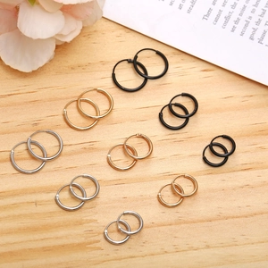 Minimalist round hoop earrings in black, gold, and silver on a rustic wooden surface