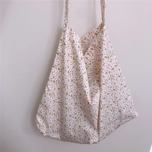 Detailed close-up of a floral cotton tote bag hanging on a minimalist grey wall background