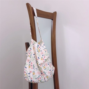 Detailed close-up of a floral canvas tote bag with colorful prints hanging on a wooden mirror