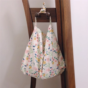 Detail of floral cotton tote bag with knot handle hanging on a wooden display stand