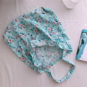 Flat lay view of a light blue floral cotton tote bag with pink flowers and a magazine