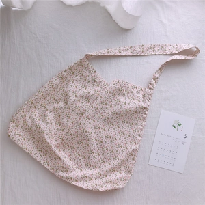 Close-up of floral cotton tote bag with vintage flower patterns on white textured background