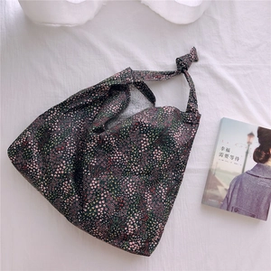 Detail of floral tote bag featuring a knotted strap design and soft cotton fabric texture