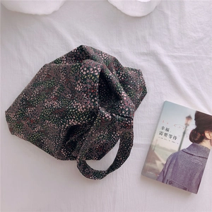 Detail view of floral cotton tote bag with small pink flowers on a white fabric surface