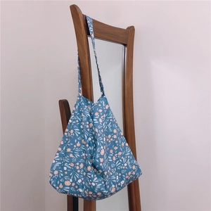 Detail of soft blue floral cotton tote bag with delicate pink blossoms on wooden chair