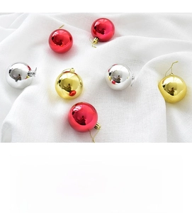 Primer plano de bolas de Navidad brillantes rojas, doradas y plateadas sobre tela blanca