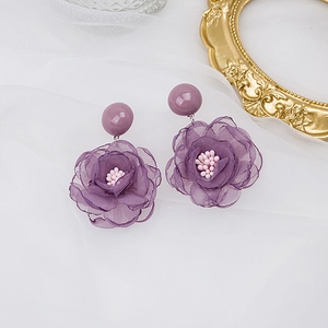 Boucles d'oreilles fleurs en mousseline violette avec perles en résine sur tissu drapé