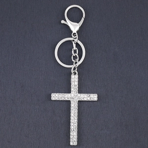 Silver vintage cross keychain with white rhinestones on a dark textured background