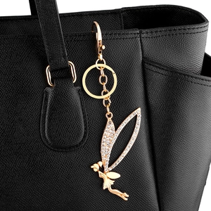Close-up of golden fairy keychain with sparkling rhinestones on a black leather handbag
