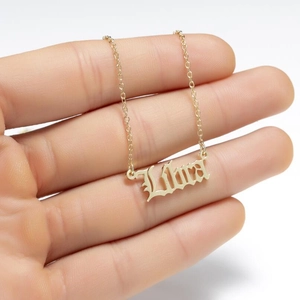 Detailed close-up of a gold Libra zodiac pendant necklace held against white background